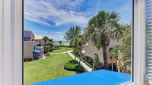 A view of a residential area with a well-maintained lawn, palm trees, and a clear blue sky. - Unit #305 Sand Cay Beach Resort Gulf View (Longboat Key)