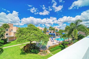 A hotel with a swimming pool, green lawns, and a clear blue sky.