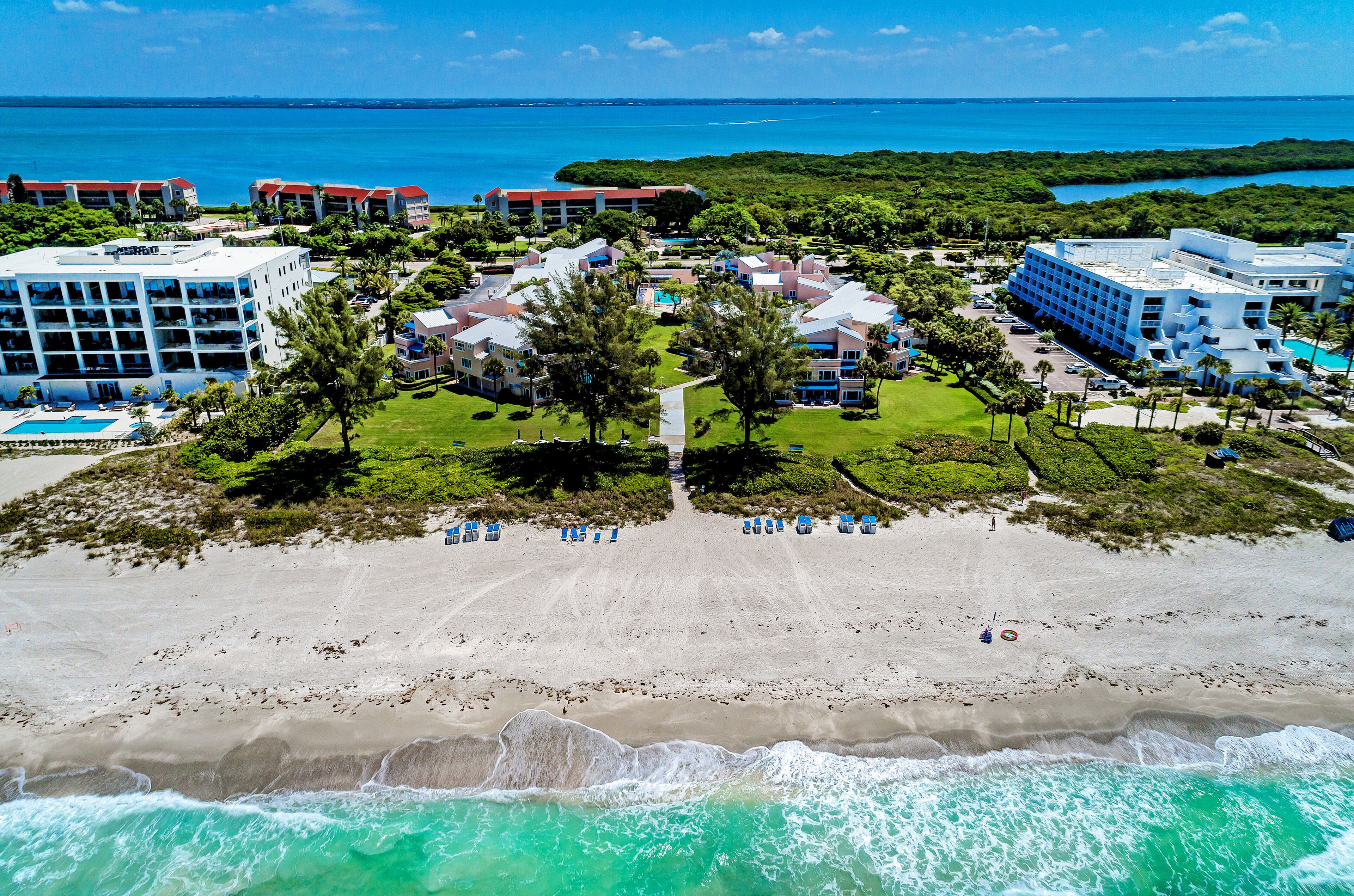 A resort with multiple buildings, a beach, and a view of the ocean.