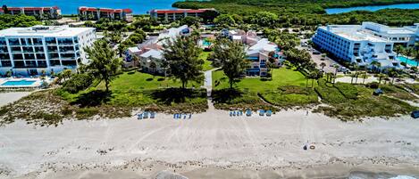 A resort with multiple buildings, a beach, and a view of the ocean.