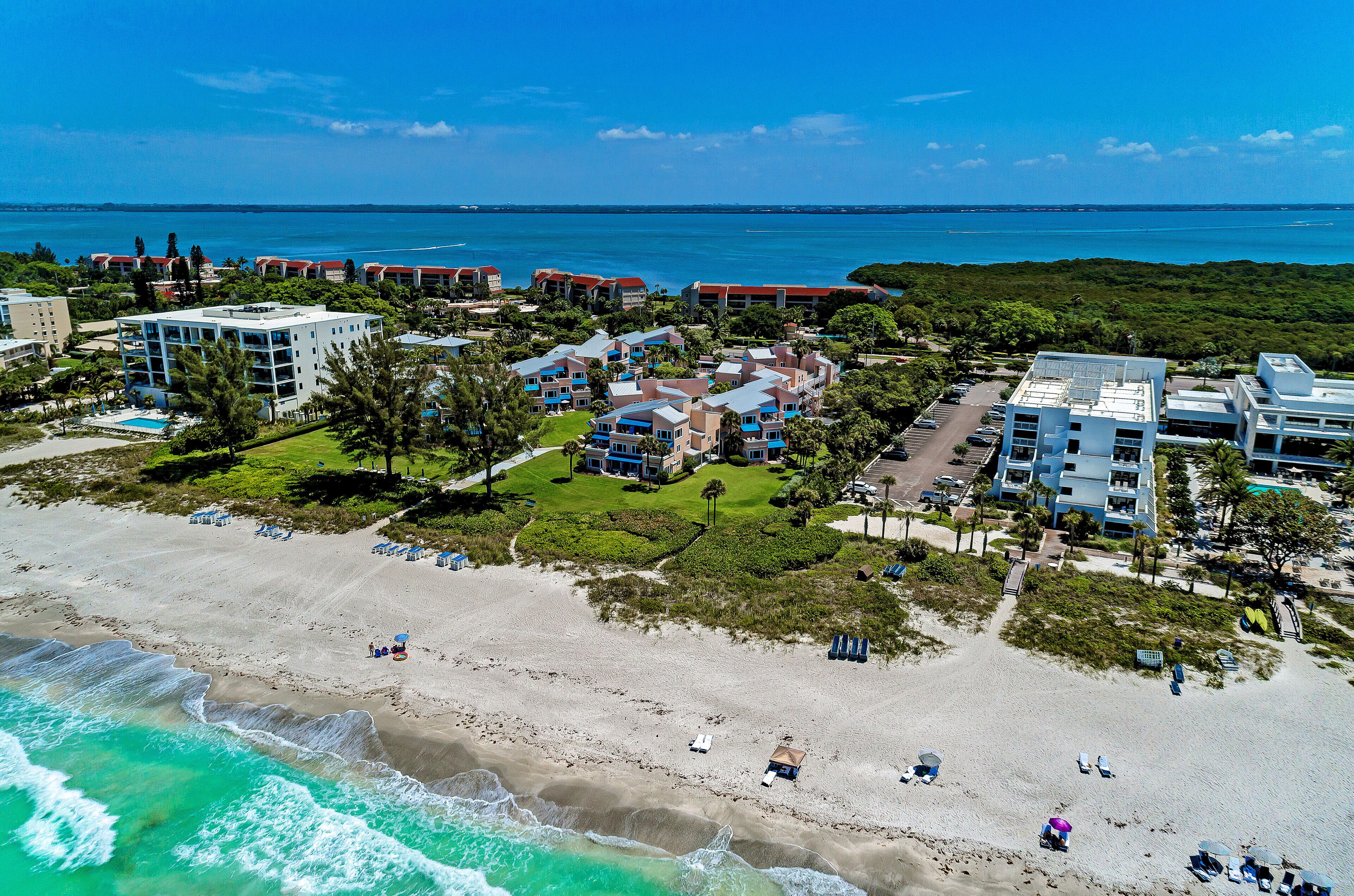 A coastal resort with beachfront villas, a pool, and a view of the ocean.