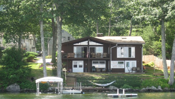 A two-story house with a dock and a boat. - Lake Winnipesaukee Waterfront! Family Friendly, Amazing View, HotTub,Kayaks+more (Alton Bay)