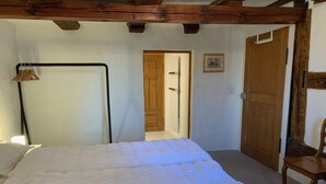 A bedroom with a large bed, wooden beams on the ceiling, a wooden door, and a small chair. - Superior Family Apartment in old house  built in 1707 (Laufen-Uhwiesen)