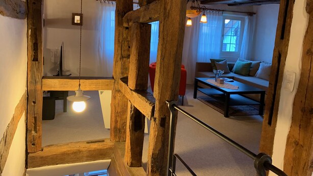 A rustic wooden interior with exposed beams, a sofa, and a table. - Superior Family Apartment in old house  built in 1707 (Laufen-Uhwiesen)