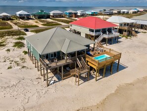 Une propriété située en bord de mer, comprenant plusieurs constructions en bois, dont un bâtiment principal avec un toit rouge et un espace piscine séparé.