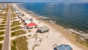 An aerial view of a coastal area with a long road, beachfront properties, and ocean views.