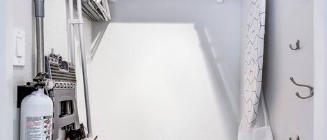 A compact, well-organized utility room with a built-in ironing station, a step ladder, and a fire extinguisher.