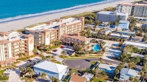 A coastal hotel with multiple buildings, a beach, and a parking area. - Fabulous 1br New Coastal Apt Steps to the Beach! - Unit D (Cocoa Beach)