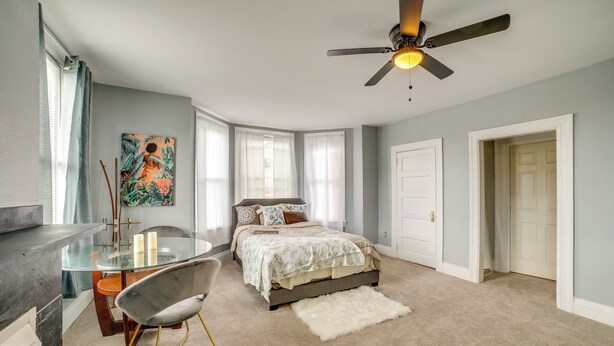 A bedroom with a bed, a glass table, a chair, a ceiling fan, and a door. - Pittsburgh Vacation Rental ~ 6 Mi to Downtown! (Pittsburgh)