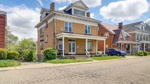 A two-story brick house with a porch, a satellite dish, and a parked blue car. - Pittsburgh Vacation Rental ~ 6 Mi to Downtown! (Pittsburgh)