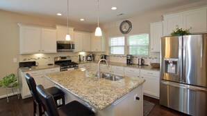 A modern kitchen with white cabinets, granite countertops, stainless steel appliances, and pendant lighting. - 3 Spacious Bedroom-Executive Town House, <br>Brand-New Construction, Duke RTP (Durham)