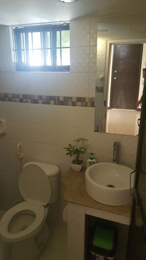 Ein Badezimmer mit Toilette, Waschbecken und einer kleinen Topfpflanze.