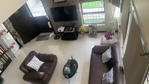 Ein geräumiges Wohnzimmer mit zwei braunen Ledersofas, einem Couchtisch und einem Fernseher.