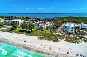 An aerial view of a coastal resort with beachfront properties, a sandy beach, and ocean views.