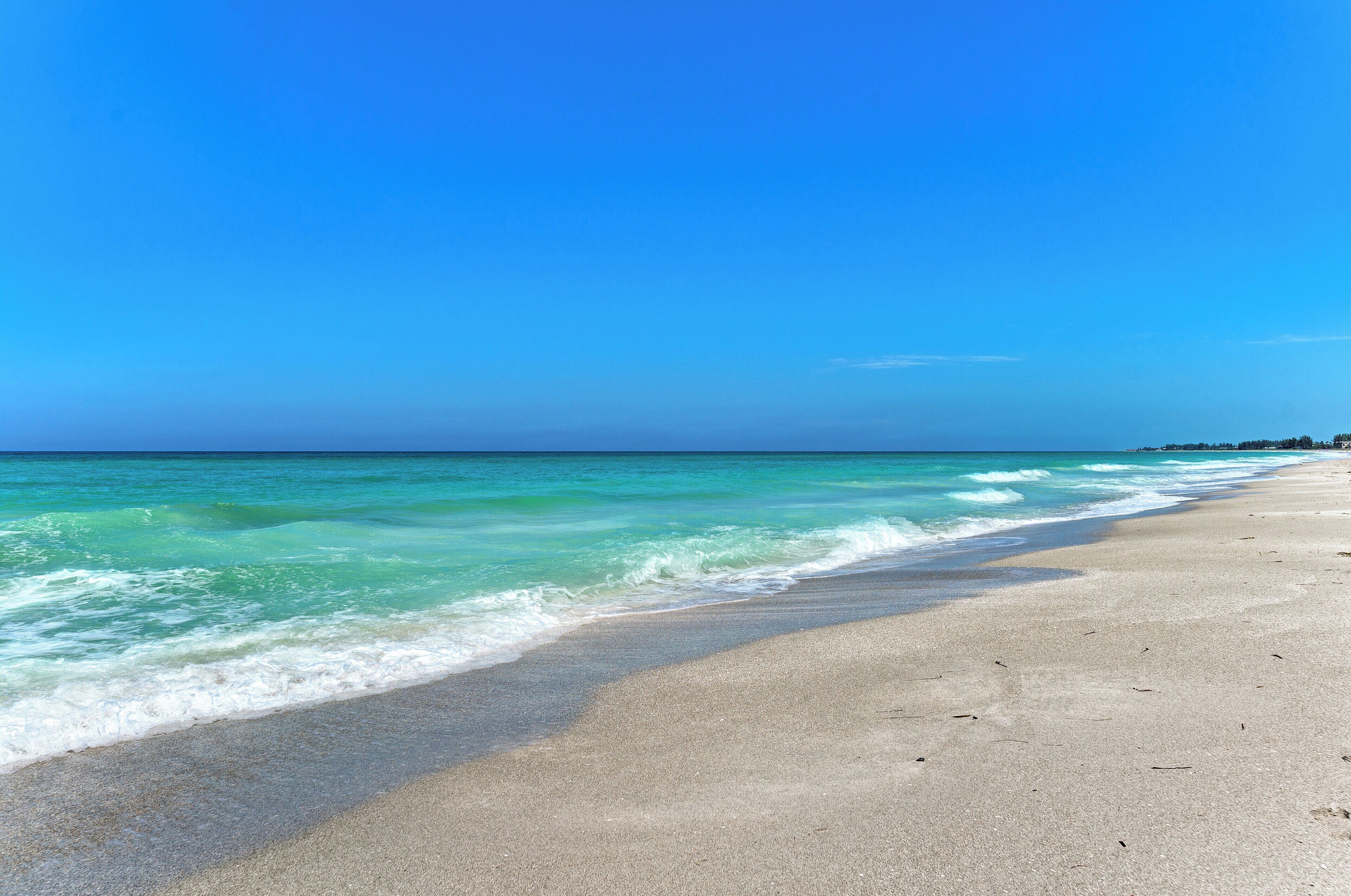 A beach with clear turquoise water and a sandy shore.