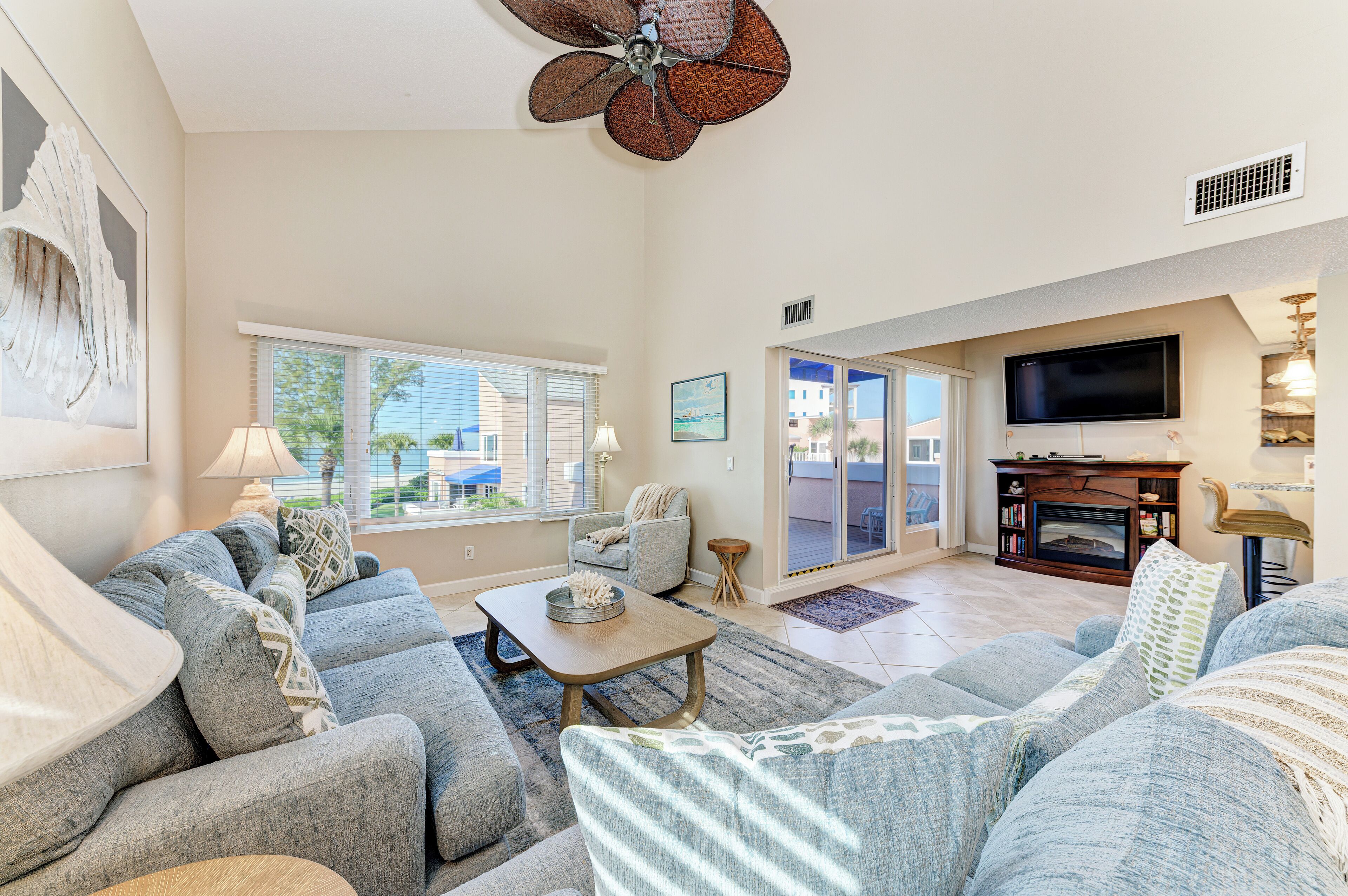 A living room with a sectional sofa, a coffee table, a fireplace, and a television mounted on the wall.