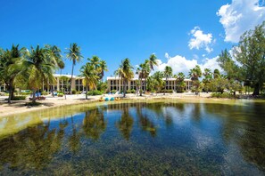 Un resort con piscina cristalina, palmeras y un edificio con varios balcones.