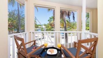 A balcony with two wooden chairs, a small table, and a glass of orange juice.
