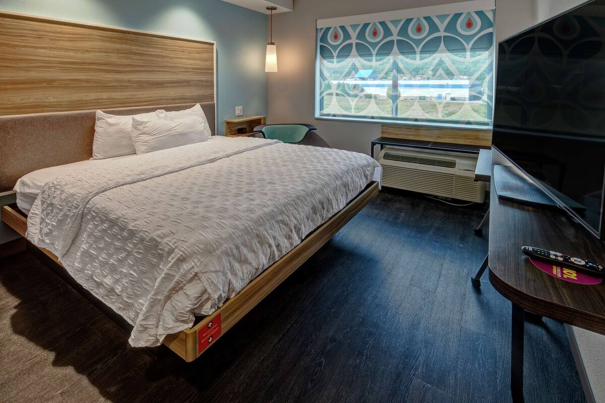 Ein Hotelzimmer mit einem großen Bett, einem Fernseher, einem Fenster mit Blick und einer Wand mit dekorativem Muster.