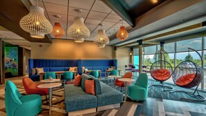 Ein stilvoller Lounge-Bereich mit Ecksofa, Sesseln in Türkis und Orange sowie Hängesesseln.