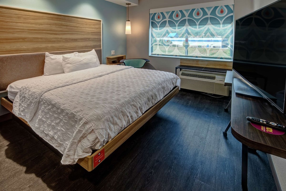 Ein Hotelzimmer mit einem großen Bett, einem Fernseher, einer Heizung und einem Fenster mit Blick.