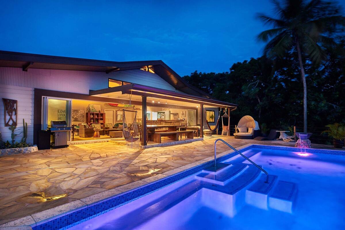 A modern house with a swimming pool, outdoor seating, and a covered patio area.
