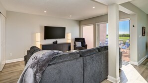 A modern living room with a sectional sofa, a flat-screen TV, and a comfortable chair. - Unit #103 Sand Cay Beach Resort Gulf Front (Longboat Key)