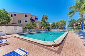 A swimming pool with blue lounge chairs and a white fence.