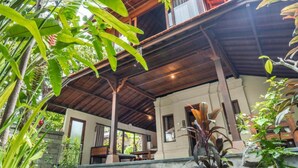 A wooden building with a covered patio area, surrounded by lush greenery. - Sari Bamboo Bungalows (Ubud)