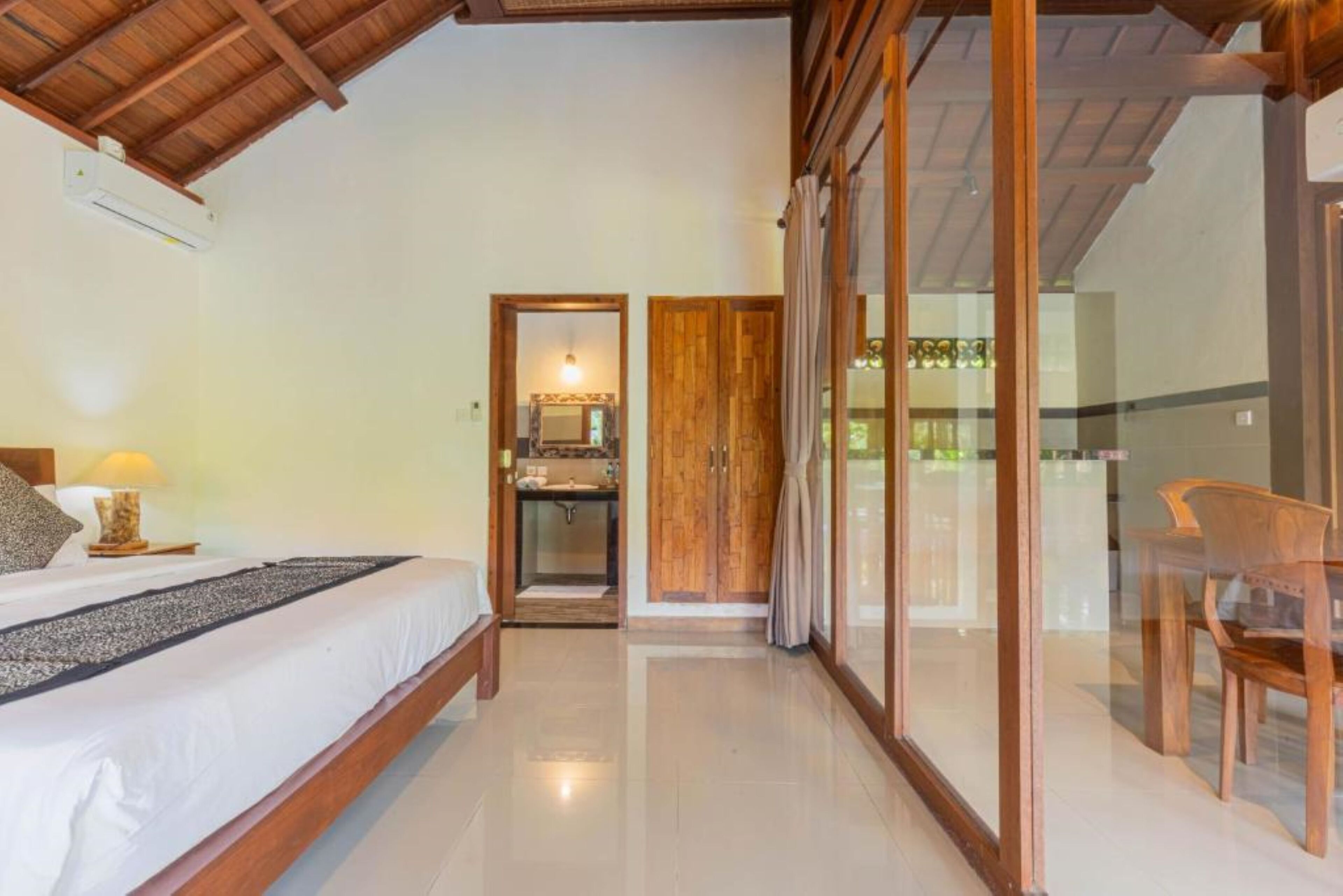 A bedroom with a bed, bedside lamp, and a bathroom visible through a door.