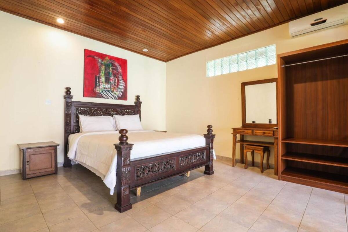 Un dormitorio con una cama de madera, una mesita de noche, un aparador y un espejo grande.