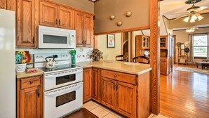 Une cuisine avec des meubles de rangement en bois, un four à micro-ondes blanc, une cuisinière et un évier.