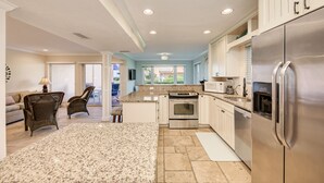 A spacious kitchen with granite countertops, stainless steel appliances, and a view to the outside. - Unit #115 Sand Cay Beach Resort Gulf View (Longboat Key)
