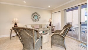 A living room with wicker furniture, a round coffee table, and a sofa with cushions. - Unit #115 Sand Cay Beach Resort Gulf View (Longboat Key)