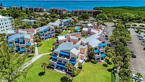 A resort with multiple buildings, a parking area, and a view of the ocean. - Unit #115 Sand Cay Beach Resort Gulf View (Longboat Key)