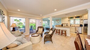 A spacious living area with a sofa, chairs, and a round coffee table. There is a kitchen area with a refrigerator, microwave, and sink. The space has large windows and a view of the outdoors. - Unit #115 Sand Cay Beach Resort Gulf View (Longboat Key)