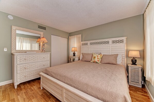 Un dormitorio con cama, cómoda y mesitas de noche.