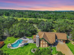 A house with a swimming pool, surrounded by a lush green landscape. - Rim Rock I Blanco, Log Cabin , Pool, Hot Tub, 10 acres of Nature to Explore (Blanco)