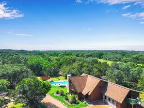 A large house with a swimming pool, surrounded by dense forest. - Rim Rock I Blanco, Log Cabin , Pool, Hot Tub, 10 acres of Nature to Explore (Blanco)