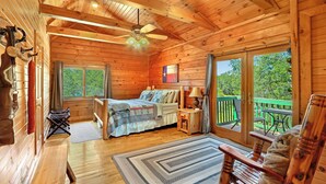 A cozy cabin with a wooden interior, a bed with a view, a dining area, and a balcony. - Rim Rock I Blanco, Log Cabin , Pool, Hot Tub, 10 acres of Nature to Explore (Blanco)