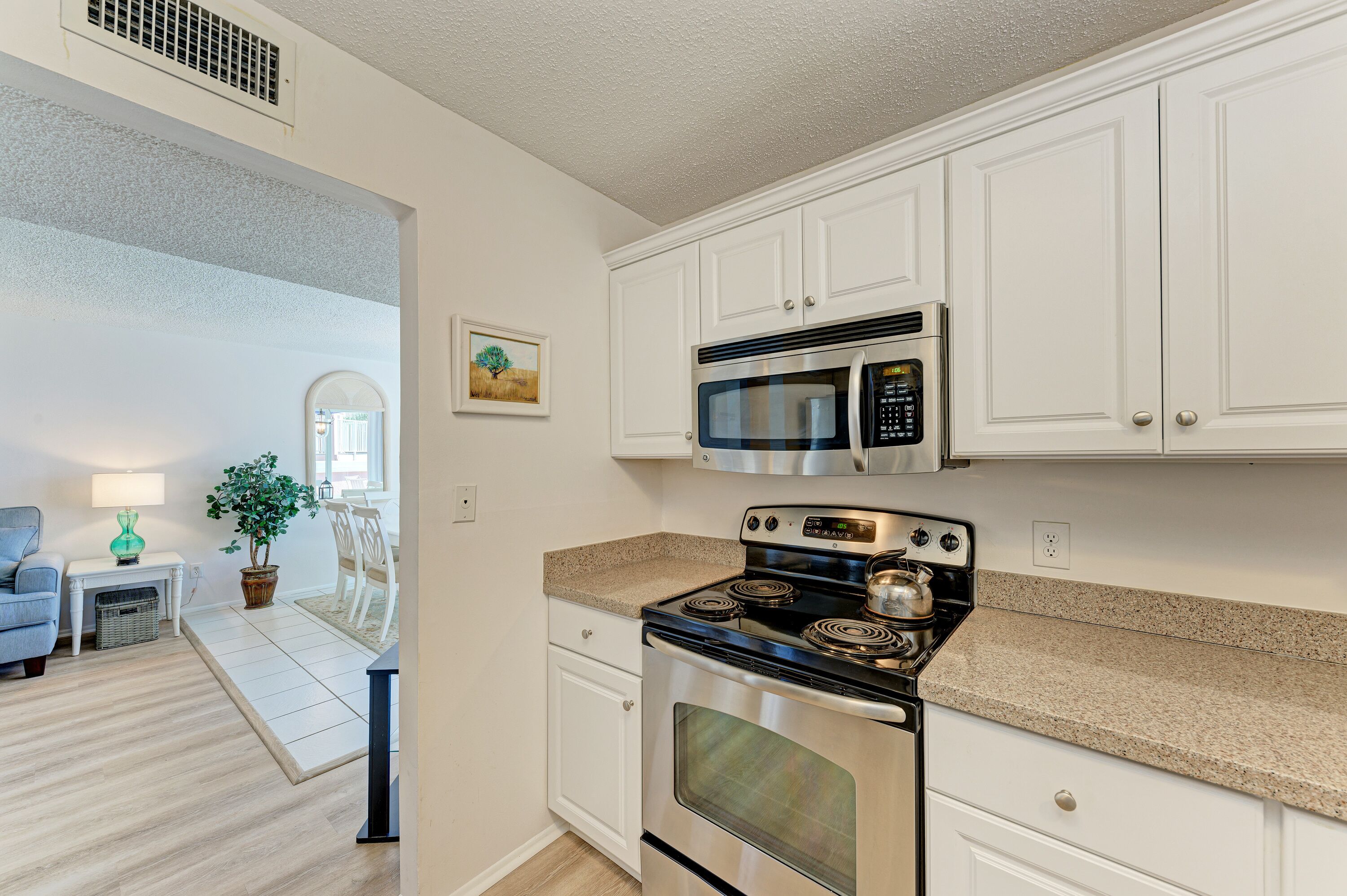 A modern kitchen with white cabinets, a stainless steel stove, and a microwave.