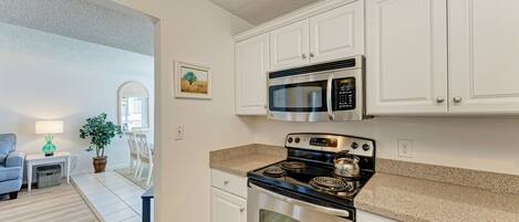 A modern kitchen with white cabinets, a stainless steel stove, and a microwave.
