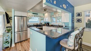 A kitchen with a central island, stainless steel appliances, and a ceiling fan. - Unit #217 Sand Cay Beach Resort Gulf Front (Longboat Key)