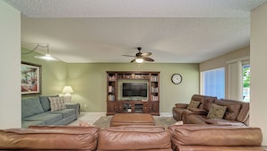 A living room with a ceiling fan, a television, and two sofas.