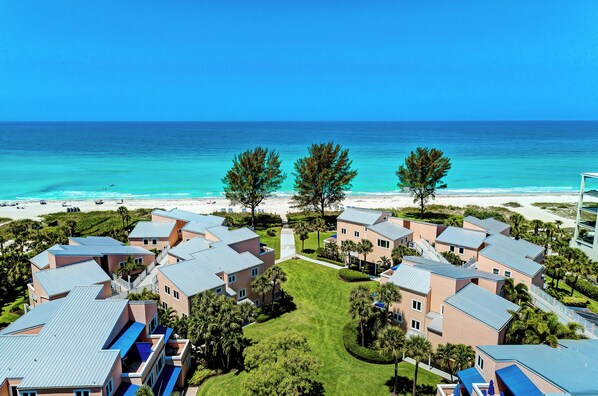 A coastal resort with multiple buildings, a beach, and a clear view of the ocean.