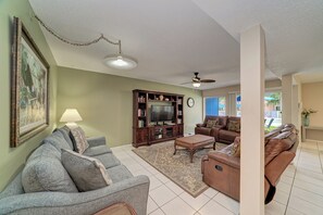 Ein Wohnzimmer mit Sofa, Couchtisch, Fernseher-Sideboard und Deckenventilator.