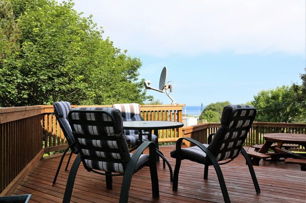 A deck with two chairs, a table, and a satellite dish.