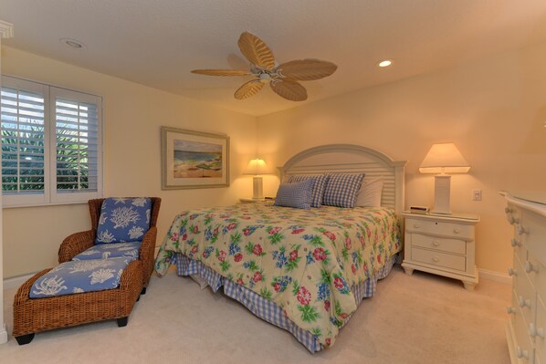 A bedroom with a bed, a chair, a nightstand, a dresser, a ceiling fan, and a window with blinds. - Unit #306 Sand Cay Beach Resort Gulf View (Longboat Key)
