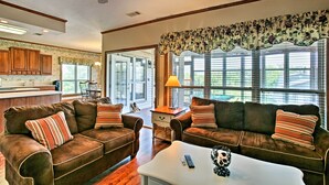 A living room with two brown leather sofas, a white coffee table, and a ceiling fan. - Private Dock w/ Lift: Waterfront New Orleans Home! (New Orleans)