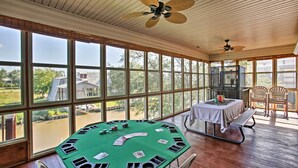 A spacious room with large windows, a green felt blackjack table, and ceiling fans. - Private Dock w/ Lift: Waterfront New Orleans Home! (New Orleans)